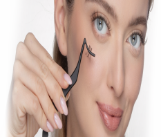 A woman delicately holds a lash applier to her face